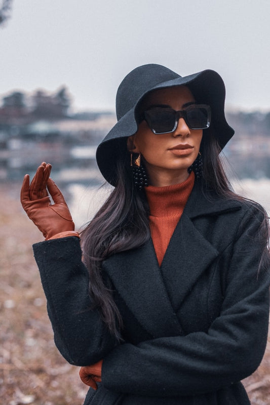 Woman in black coat with sunglasses and hat