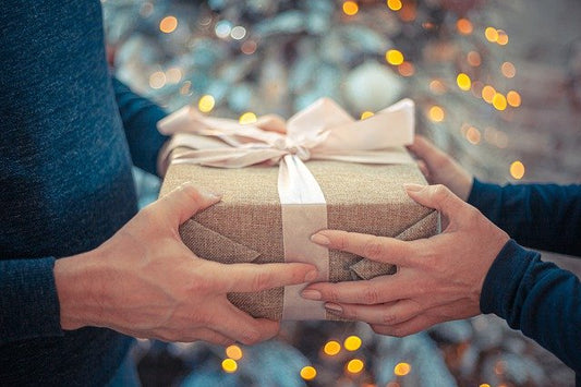 A person handing a Christmas gift to another person