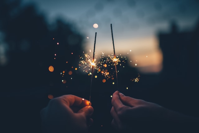Two hands holding lit sparklers