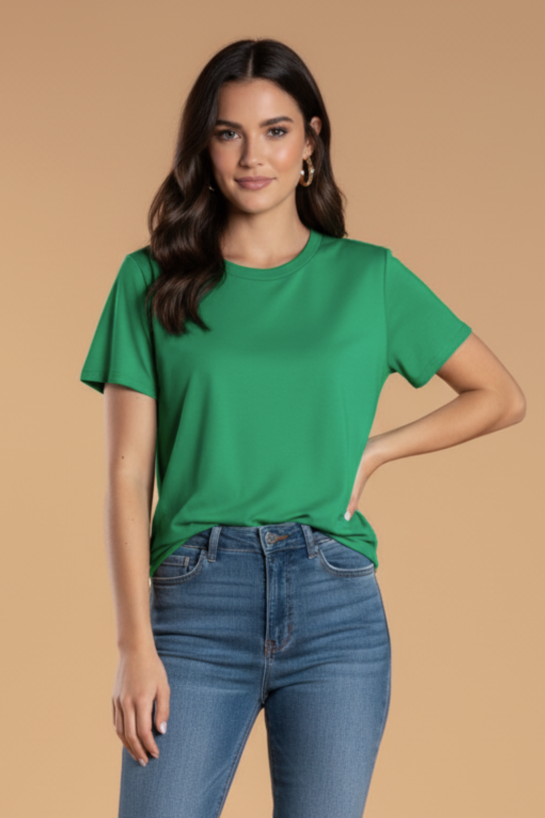 Woman wearing a green t-shirt and blue jeans against a beige background
